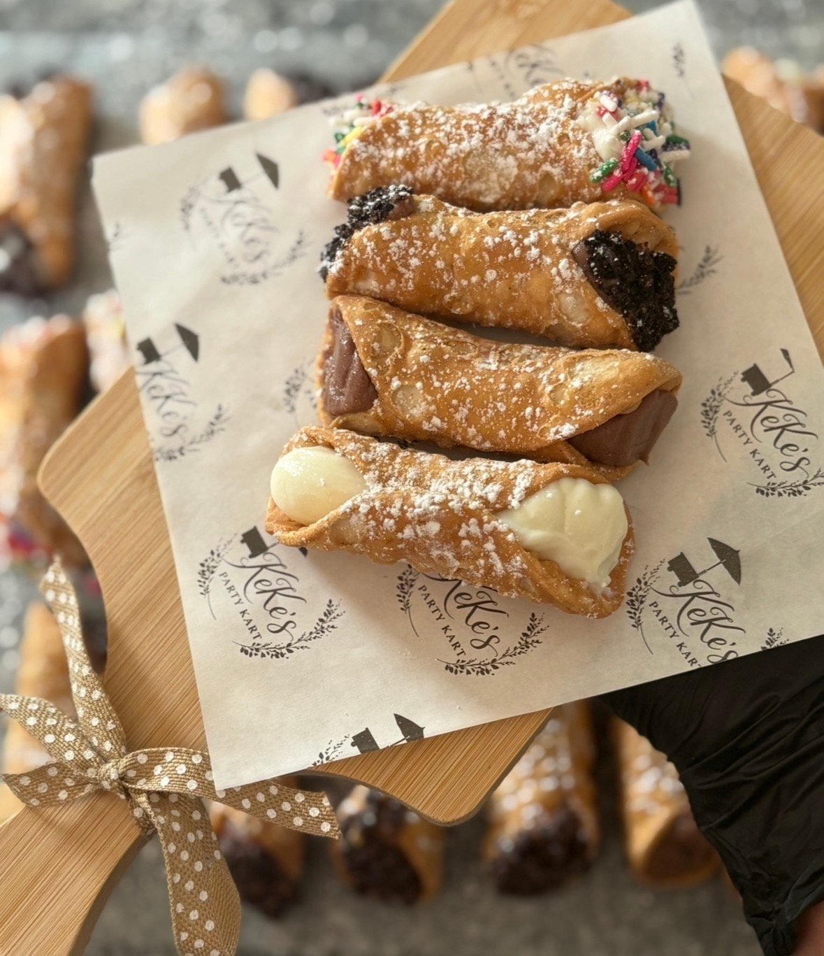 Assorted cannoli stacked on branded KeKe's paper
